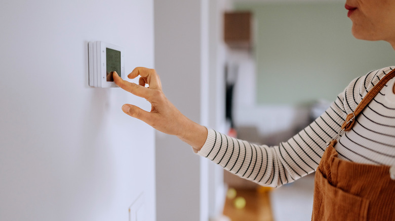 woman adjusting the temperature on her home thermostat