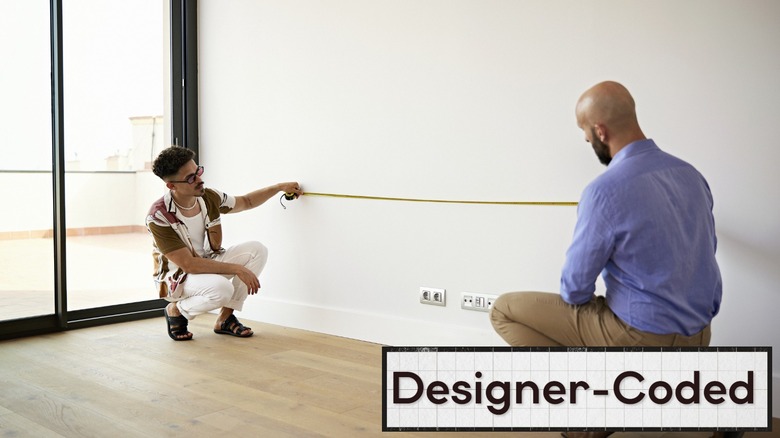 two people measuring a wall together