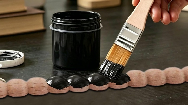 Person painting wood bobbin trim black before installing