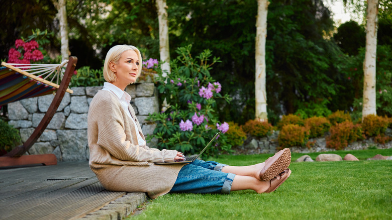 A woman sitting on a patio and working on a laptop