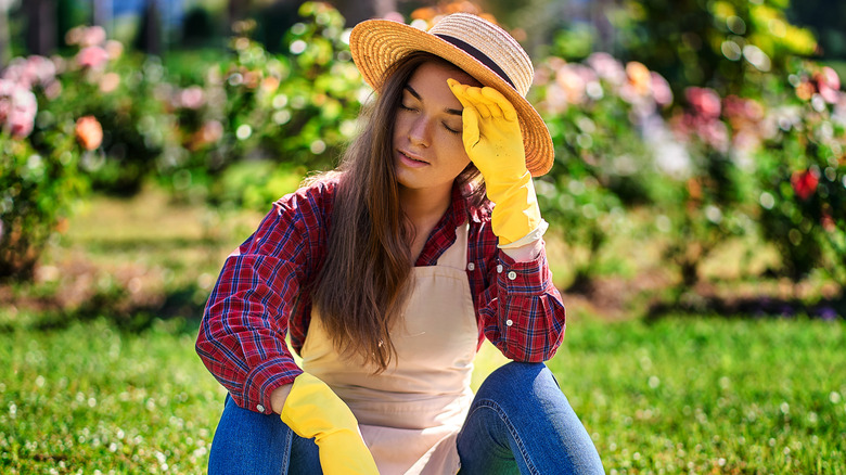 Frustrated woman sitting on grass on a sunny day