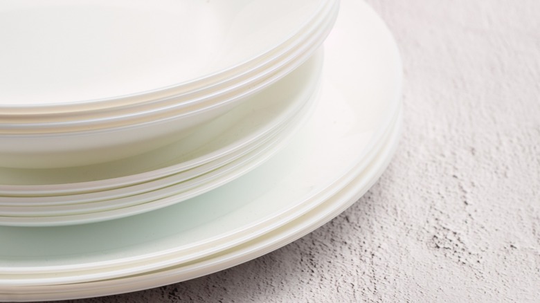 White Vitrelle plates stacked on white surface.