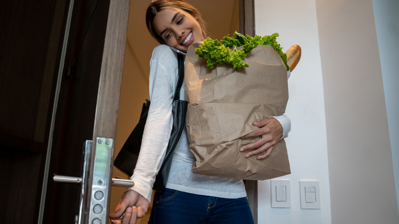 Woman with groceries unlocking door