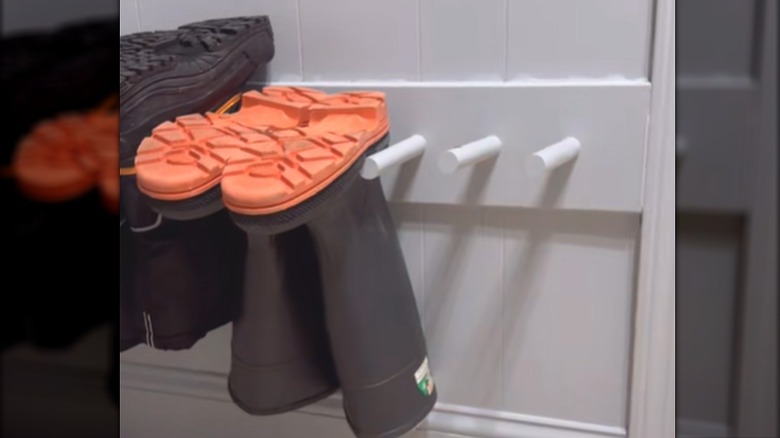 Work boots hanging upside down between DIY pegs on home wall