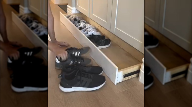 Man hiding sneakers in DIY hidden bottom drawer beneath white cabinets