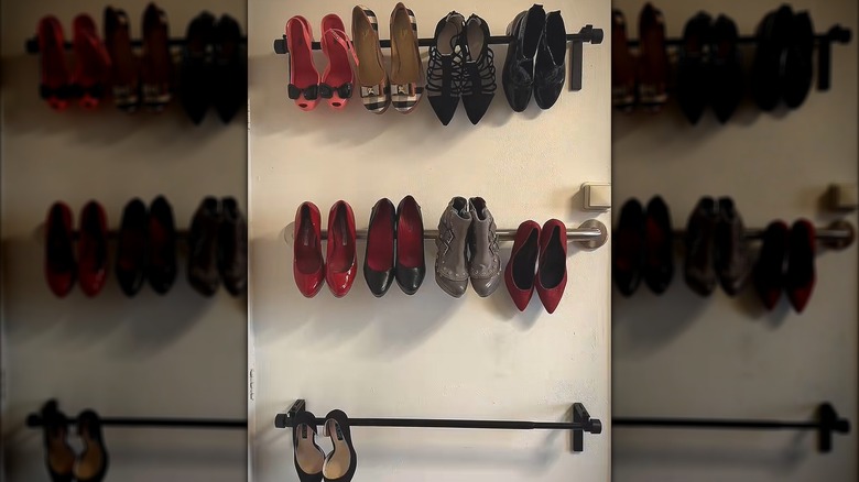 Formal women's shoes hanging over towel rods on white wall