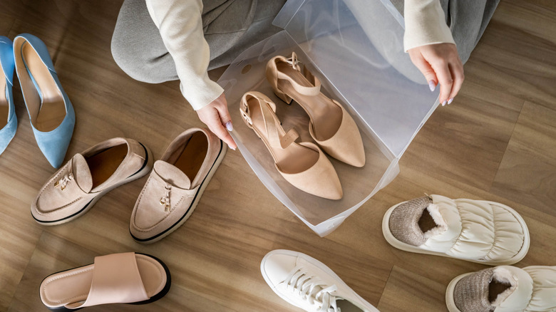 Woman storing individual pairs of shoes in plastic container on wood floor