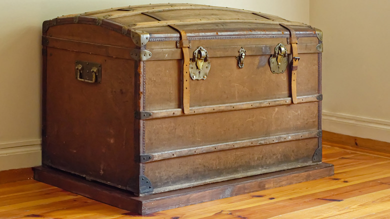 Leather and iron vintage trunk in house corner on classic hardwood floor