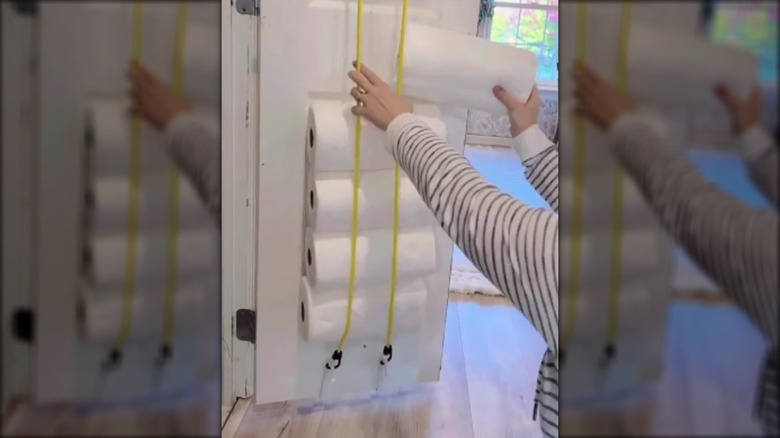Woman adding her paper towels to her bungee cord storage solution