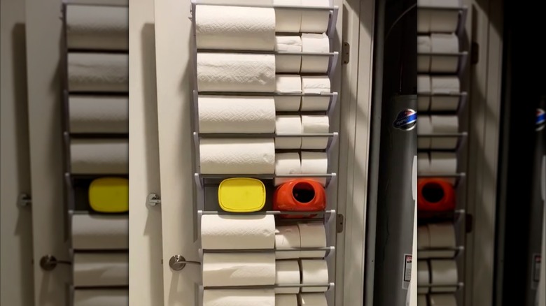 Over-the-door shoe rack filled with toilet paper rolls, paper towel rolls, and cleaning products
