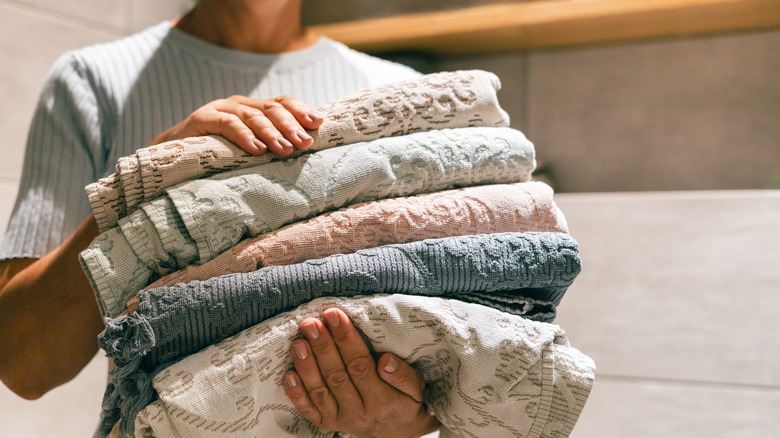 A person holding a folded stack of towels
