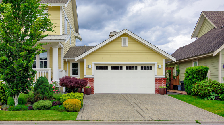 A yellow house with a concrete driveway