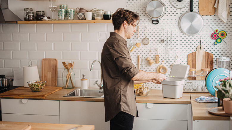 a man scrapes food waste into a countertop compost bin
