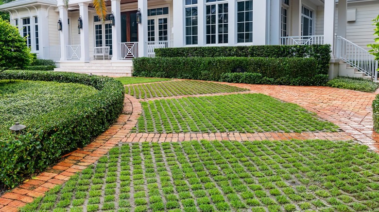 Curved driveway constructed of grass pavers and brick in front of a large house
