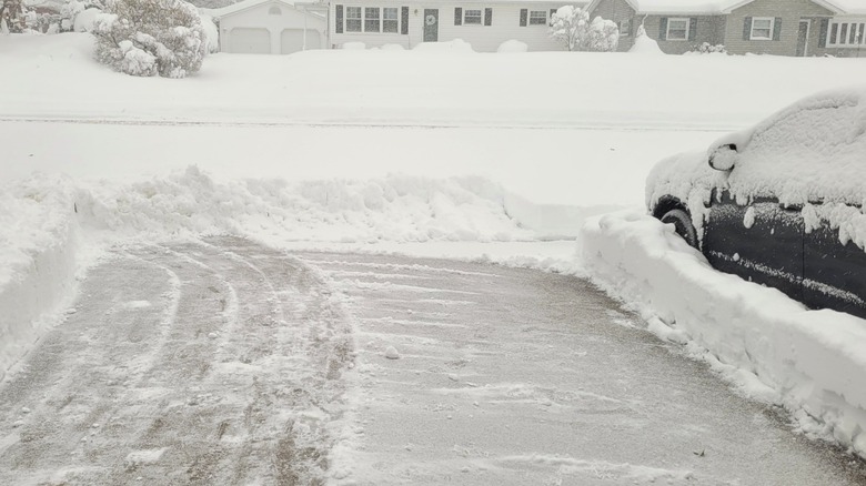 cleared patch of snowy icy driveway next to snow-covered car
