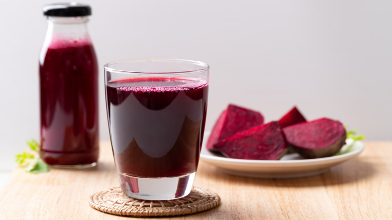 glass of beet juice with cut beets on table
