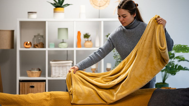 A woman in the process of organizing a soft, yellow blanket