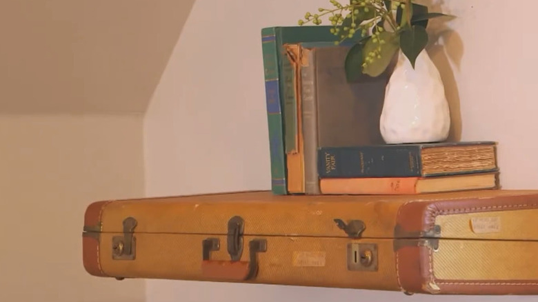 Brown leather suitcase attached to the wall as a shelf