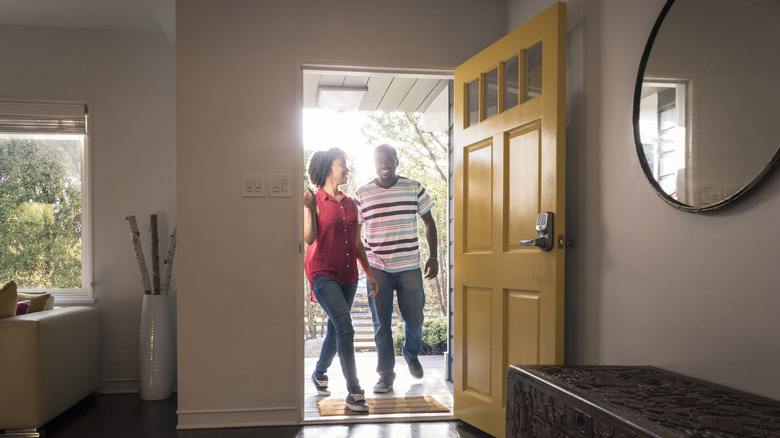 Couple walking into home with blank front door, no decorations