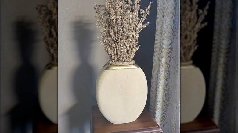 Vases made out of an old detergent container with a stone effect and dried flowers in it