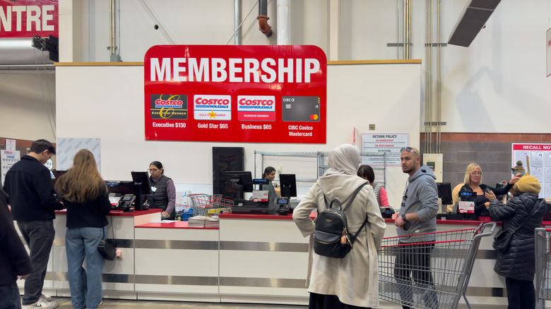 Shoppers stand near a Costco membership sign