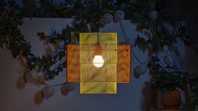 A yellow and orange SOLVINDEN Ceiling lamp from IKEA illuminates a patio at night