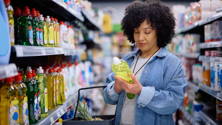 Woman in store reading label on bottle of yellow liquid soap