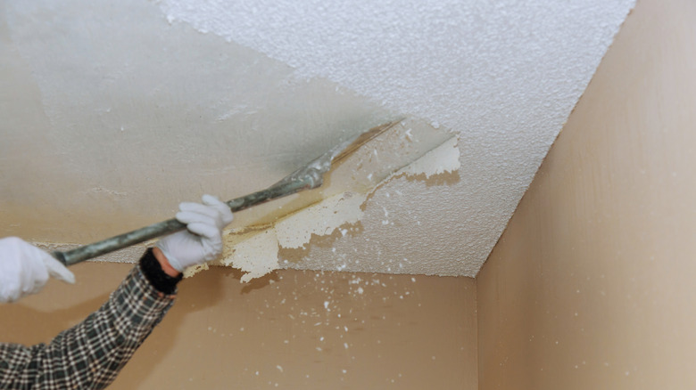 Contractor scraping popcorn texture from ceiling.