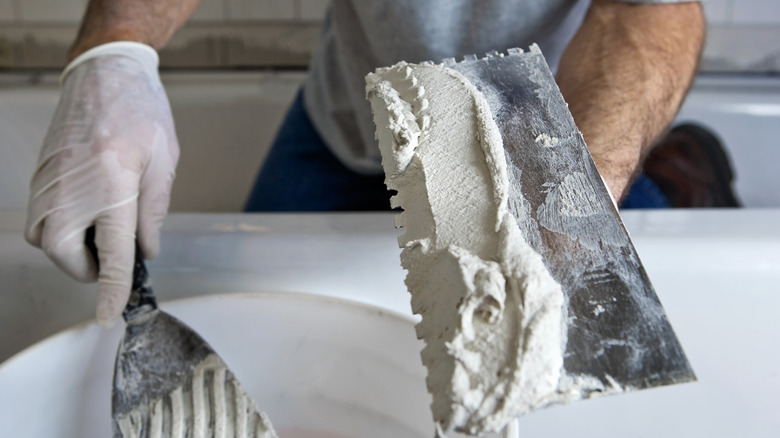 man with trowel getting ready to tile in a bathroom