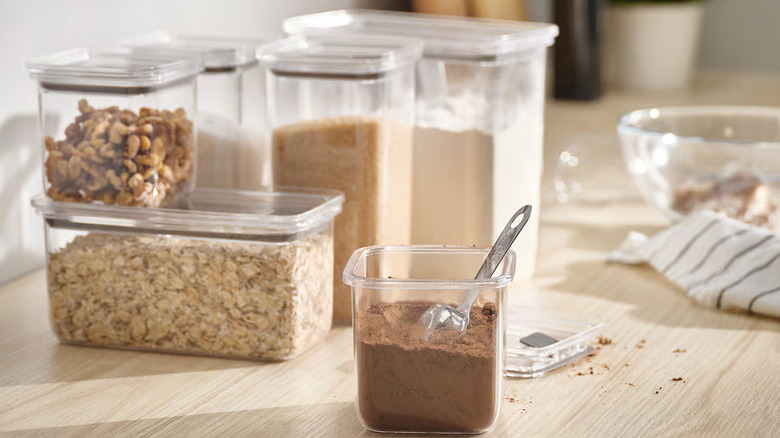 Plastic lidded food storage containers sit on a wooden countertop