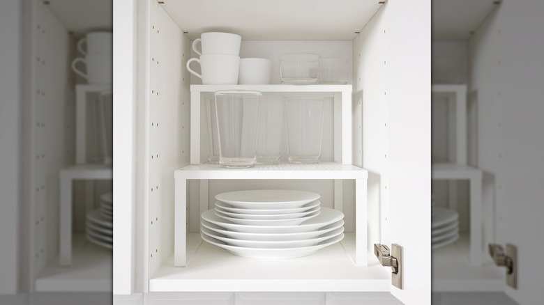 Assorted mugs, glasses, and dishes sit on a white VARIERA shelf insert from IKEA