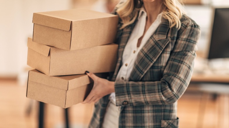 Person carrying stack of empty cardboard shoeboxes