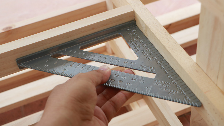 Person verifying a right angle on a wood frame using a speed square