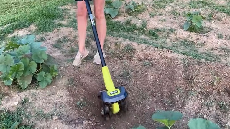 Woman eliminating weeds using a Ryobi handheld tiller