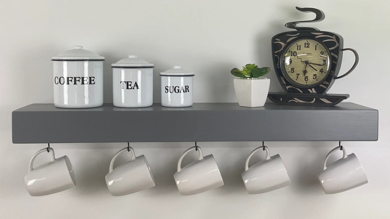 Screw hooks under kitchen shelf holding variety of mugs