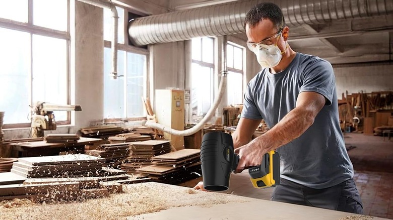a man using a GREENFURY cordless leaf blower to clean a table