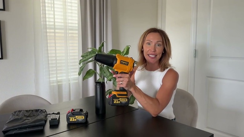 a female holding the Vopot cordless leaf blower with its accessories on the table