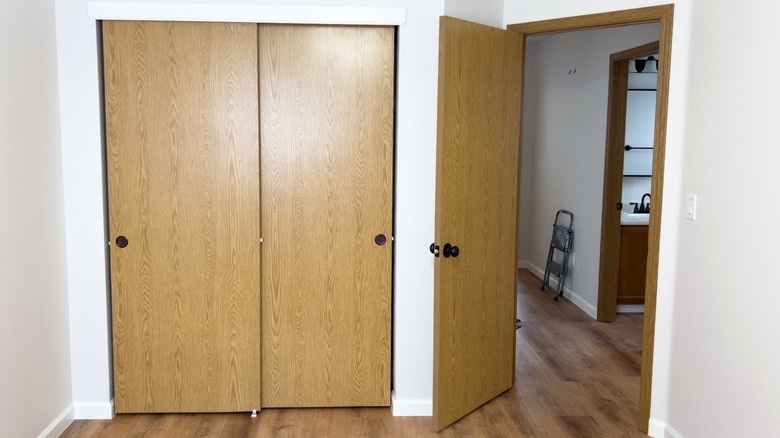 A bedroom door is open next to a set of dated sliding closet doors