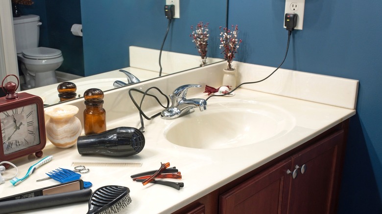 Small bathroom counter cluttered with hair care products