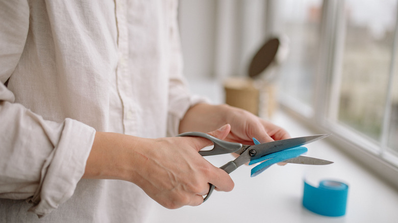 Woman cutting folded material with scissors.