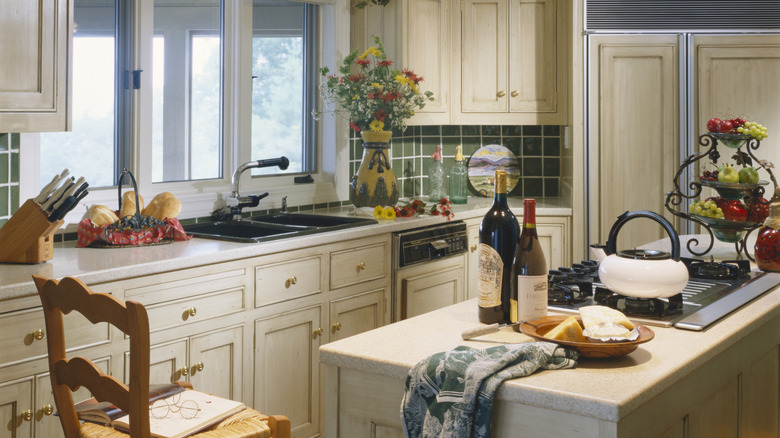 A kitchen in the 1990s with green tile and light wood cabinets
