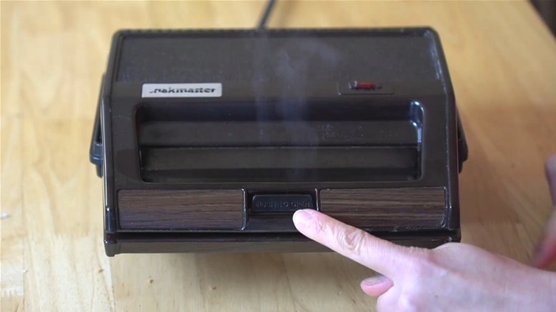 Person pressing open button on a Clark Snakmaster making a toasted sandwich