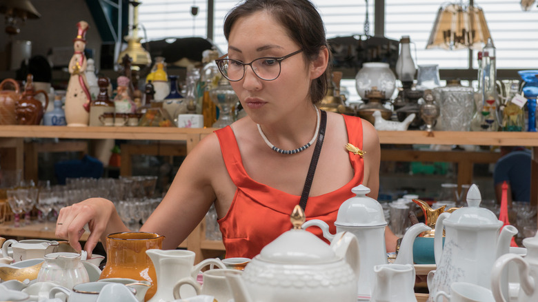 Woman searching through table of dishes at flea market