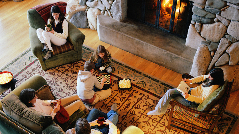 A conversation first living space with people on the couch, side chairs, and rug