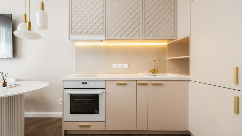 A small beige modern kitchen with under-cabinet lighting