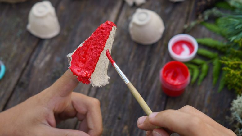 Person painting piece of egg carton with red paint