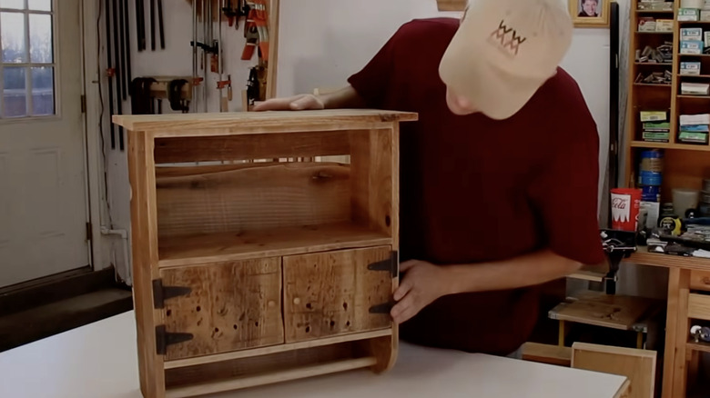 Steve Ramsey, a woodworker, holding his DIY wooden pallet for bathroom toilet paper storage