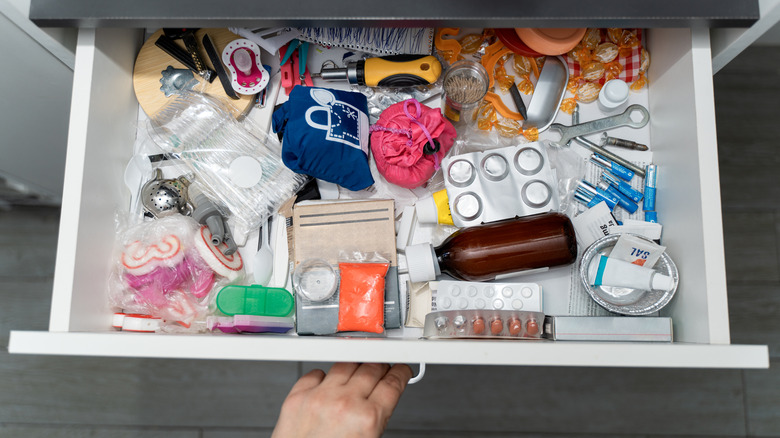 A messy drawer full of accessories, medication, and more