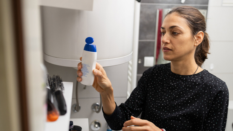 A woman attempting to organize items on a bathroom shelf