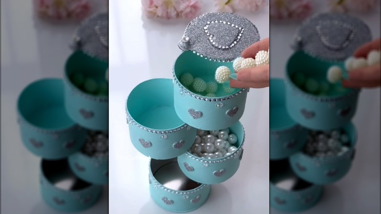 Person putting small items into a storage tower made from Pringles cans